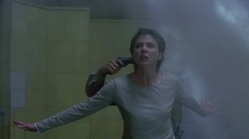 Movie still from “The Siege” (1998), directed by Edward Zwick – A woman holding a hair dryer on her shoulder; Medium shot, Low angle