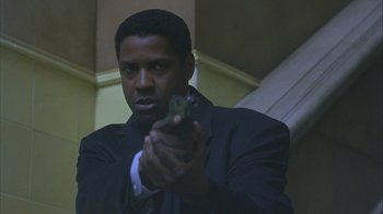Movie still from “The Siege” (1998), directed by Edward Zwick – A man in a suit holding a gun in his hand; Close Up shot, Low angle
