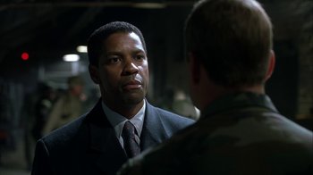 Movie still from “The Siege” (1998), directed by Edward Zwick – A man in a suit and tie talking to another man in a suit and tie; Close Up shot, Over the shoulder angle
