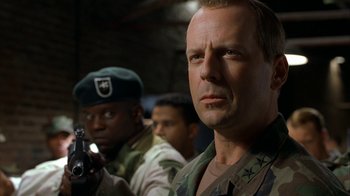 Movie still from “The Siege” (1998), directed by Edward Zwick – A man with a gun in his hand and other men in the background; Close Up shot, Low angle