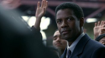 Movie still from “The Siege” (1998), directed by Edward Zwick – A man in a suit and tie raising his right hand; Close Up shot, Low angle