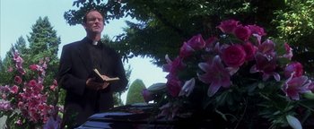 Movie still from “The Sisterhood of the Traveling Pants” (2005), directed by Ken Kwapis – A priest standing in front of a table with flowers; Medium shot, Low angle