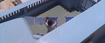 Movie still from “The Sisterhood of the Traveling Pants” (2005), directed by Ken Kwapis – A man hanging clothes on a clothesline outside; Wide shot, Overhead angle