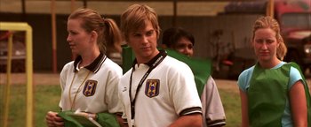 Movie still from “The Sisterhood of the Traveling Pants” (2005), directed by Ken Kwapis – A man in a white shirt is standing in front of other people; Medium shot, Over the shoulder angle