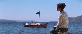 Movie still from “The Sisterhood of the Traveling Pants” (2005), directed by Ken Kwapis – A man sitting in front of a boat in the water; Wide shot, Low angle