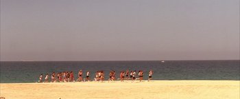 Movie still from “The Sisterhood of the Traveling Pants” (2005), directed by Ken Kwapis – A group of people running on the beach near the ocean; Extreme Wide shot, High angle