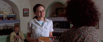 Movie still from “The Sisterhood of the Traveling Pants” (2005), directed by Ken Kwapis – A young woman holding a box in her hands; Medium shot, Over the shoulder angle