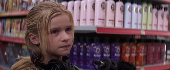 Movie still from “The Sisterhood of the Traveling Pants” (2005), directed by Ken Kwapis – A young girl is standing in front of a shelf of hair products; Close Up shot, Over the shoulder angle