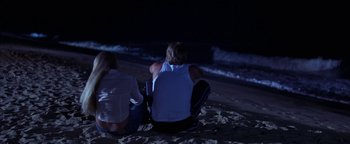 Movie still from “The Sisterhood of the Traveling Pants” (2005), directed by Ken Kwapis – A man and a woman sitting on the beach at night; Wide shot, High angle