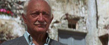 Movie still from “The Sisterhood of the Traveling Pants” (2005), directed by Ken Kwapis – An old man with a mustache is standing in front of a building; Close Up shot, Low angle