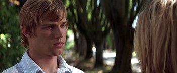 Movie still from “The Sisterhood of the Traveling Pants” (2005), directed by Ken Kwapis – A young man is standing in front of some trees; Close Up shot, Low angle