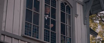 Movie still from “The Sisters Brothers” (2018), directed by Jacques Audiard – A man in a tuxedo looking out of a window; Medium shot, Low angle