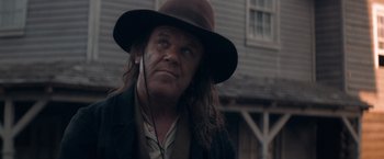 Movie still from “The Sisters Brothers” (2018), directed by Jacques Audiard – A man in a hat and a jacket looking to his left; Close Up shot, Over the shoulder angle