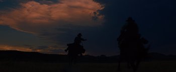 Movie still from “The Sisters Brothers” (2018), directed by Jacques Audiard – A man riding a horse in a field at night; Extreme Wide shot, Low angle