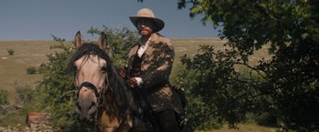 Movie still from “The Sisters Brothers” (2018), directed by Jacques Audiard – A man riding on the back of a brown horse; Medium shot, Low angle