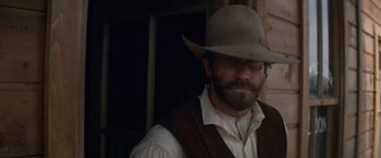Movie still from “The Sisters Brothers” (2018), directed by Jacques Audiard – A man with a beard wearing a cowboy hat; Close Up shot, Over the shoulder angle