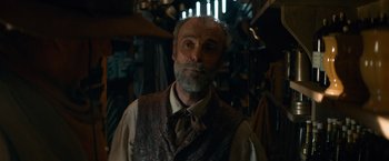 Movie still from “The Sisters Brothers” (2018), directed by Jacques Audiard – An older man with a gray beard wearing a vest and tie; Medium shot, Low angle