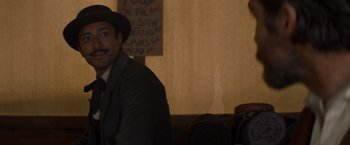 Movie still from “The Sisters Brothers” (2018), directed by Jacques Audiard – A man wearing a hat and a suit; Medium shot, Over the shoulder angle