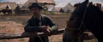 Movie still from “The Sisters Brothers” (2018), directed by Jacques Audiard – A man standing next to a horse in a field; Medium shot, Over the shoulder angle