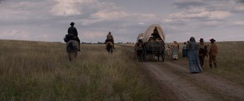 Movie still from “The Sisters Brothers” (2018), directed by Jacques Audiard – A group of people riding on the back of a covered wagon; Wide shot, Low angle