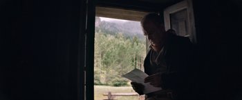 Movie still from “The Sisters Brothers” (2018), directed by Jacques Audiard – A man standing in front of a window looking at a piece of paper; Medium shot, Low angle