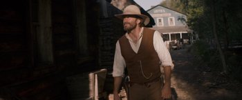 Movie still from “The Sisters Brothers” (2018), directed by Jacques Audiard – A man with a beard and a hat is walking; Medium shot, Low angle