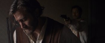Movie still from “The Sisters Brothers” (2018), directed by Jacques Audiard – A man with a gun in his hand and a man with a gun in his other hand; Close Up shot, Over the shoulder angle