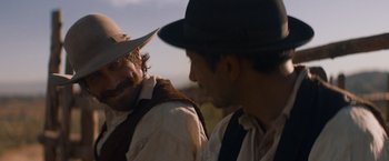 Movie still from “The Sisters Brothers” (2018), directed by Jacques Audiard – Two men in hats and vests talking to each other; Close Up shot, Over the shoulder angle