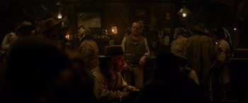 Movie still from “The Sisters Brothers” (2018), directed by Jacques Audiard – A group of people sitting in a room; Medium shot, Over the shoulder angle
