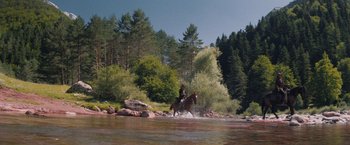 Movie still from “The Sisters Brothers” (2018), directed by Jacques Audiard – A man riding on the back of a horse through a river; Extreme Wide shot, Low angle