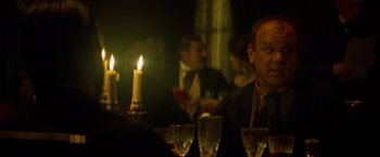 Movie still from “The Sisters Brothers” (2018), directed by Jacques Audiard – A man sitting at a table with a candle in the middle of the table; Close Up shot, Over the shoulder angle