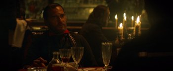 Movie still from “The Sisters Brothers” (2018), directed by Jacques Audiard – A man sitting at a table with a glass of red wine; Close Up shot, Over the shoulder angle