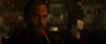 Movie still from “The Sisters Brothers” (2018), directed by Jacques Audiard – A person wearing a suit and tie; Close Up shot, Over the shoulder angle