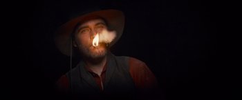 Movie still from “The Sisters Brothers” (2018), directed by Jacques Audiard – A man with a hat and a beard is smoking a cigarette; Close Up shot, Low angle