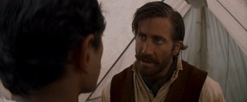 Movie still from “The Sisters Brothers” (2018), directed by Jacques Audiard – A man with long hair and a goatee talking to another man with long hair and a goatee; Close Up shot, Over the shoulder angle