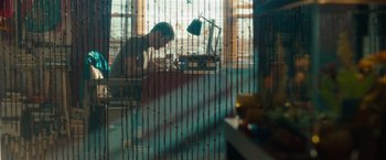 Movie still from “The Skeleton Twins” (2014), directed by Craig Johnson – A man sitting at a desk in front of a lamp; Wide shot, Low angle