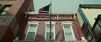 Movie still from “The Skeleton Twins” (2014), directed by Craig Johnson – An american flag is flying on a pole outside a building; Extreme Wide shot, Low angle