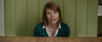 Movie still from “The Skeleton Twins” (2014), directed by Craig Johnson – A woman sitting in front of a wooden table; Close Up shot, Over the shoulder angle