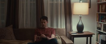 Movie still from “The Skeleton Twins” (2014), directed by Craig Johnson – A man sitting on top of a couch writing on a book; Medium shot, Over the shoulder angle