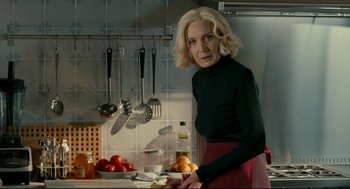Movie still from “The Skin I Live In” (2011), directed by Pedro Almodóvar – A woman standing in front of a counter in a kitchen; Medium shot, Over the shoulder angle