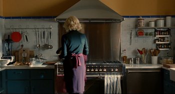 Movie still from “The Skin I Live In” (2011), directed by Pedro Almodóvar – A woman standing in front of an oven in a kitchen; Wide shot, Over the shoulder angle
