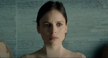 Movie still from “The Skin I Live In” (2011), directed by Pedro Almodóvar – A young woman with dark brown hair and a bare face; Close Up shot, Low angle