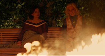 Movie still from “The Skin I Live In” (2011), directed by Pedro Almodóvar – Two women sitting on a bench in front of a fire pit; Medium shot, High angle