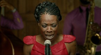 Movie still from “The Skin I Live In” (2011), directed by Pedro Almodóvar – A woman in a red dress singing into a microphone; Close Up shot, Overhead angle