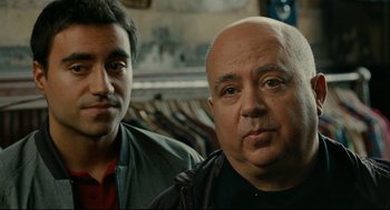 Movie still from “The Skin I Live In” (2011), directed by Pedro Almodóvar – Two men standing next to each other in front of a row of clothes; Close Up shot, Over the shoulder angle
