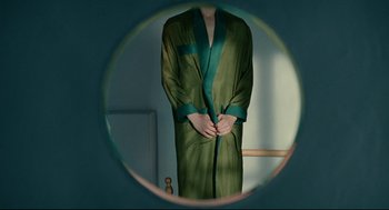 Movie still from “The Skin I Live In” (2011), directed by Pedro Almodóvar – A person in a green robe is seen in a mirror; Medium shot, Overhead angle