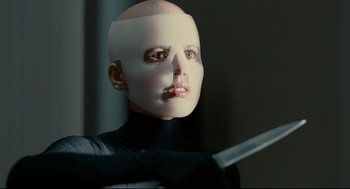 Movie still from “The Skin I Live In” (2011), directed by Pedro Almodóvar – A person with a mask on and a sword; Close Up shot, Over the shoulder angle