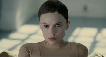 Movie still from “The Skin I Live In” (2011), directed by Pedro Almodóvar – A young woman with short black hair wearing a tan shirt; Close Up shot, Over the shoulder angle