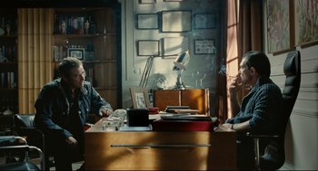 Movie still from “The Skin I Live In” (2011), directed by Pedro Almodóvar – Two people sitting at a table in front of a lamp; Medium shot, Over the shoulder angle