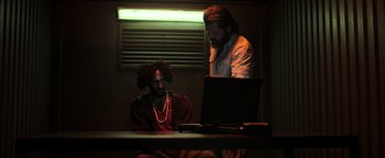 Movie still from “Sicario: Day of the Soldado” (2018), directed by Stefano Sollima – Two men sitting in front of a laptop computer in a dark room; Medium shot, Low angle